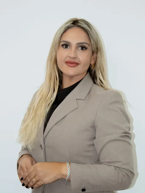 Gabriela Felipe, de blazer bege e camisa preta, diante de uma parede clara